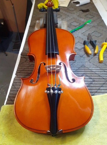 Violino restaurado sobre a bancada de trabalho do luthier